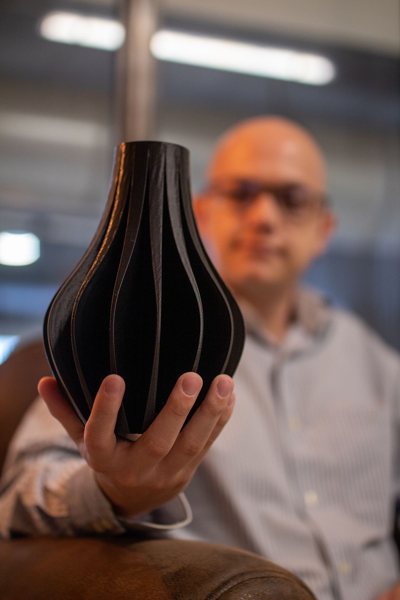 Une personne tient un objet sombre aux courbes verticales